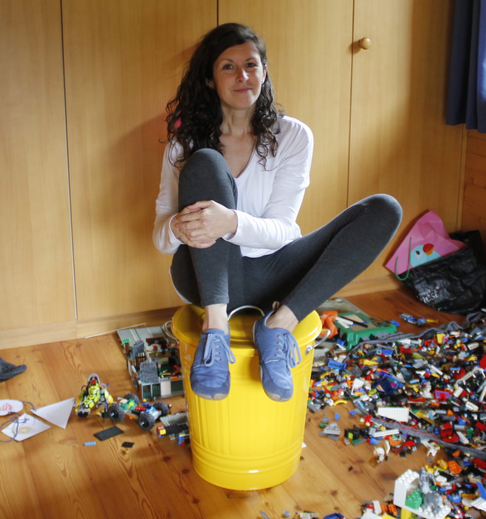 woman sitting on bin surrounded by kids lego