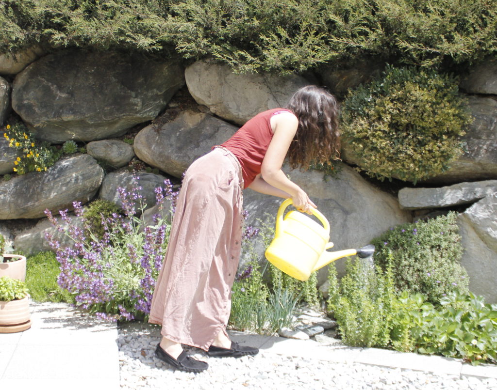 woman watering plants wearing barefoot shoes